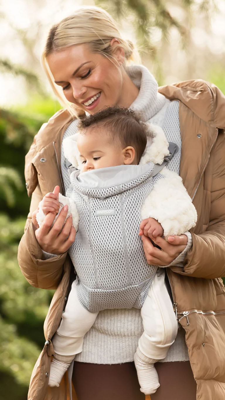 A mother carrying her baby in a BABYGO carrier outdoors