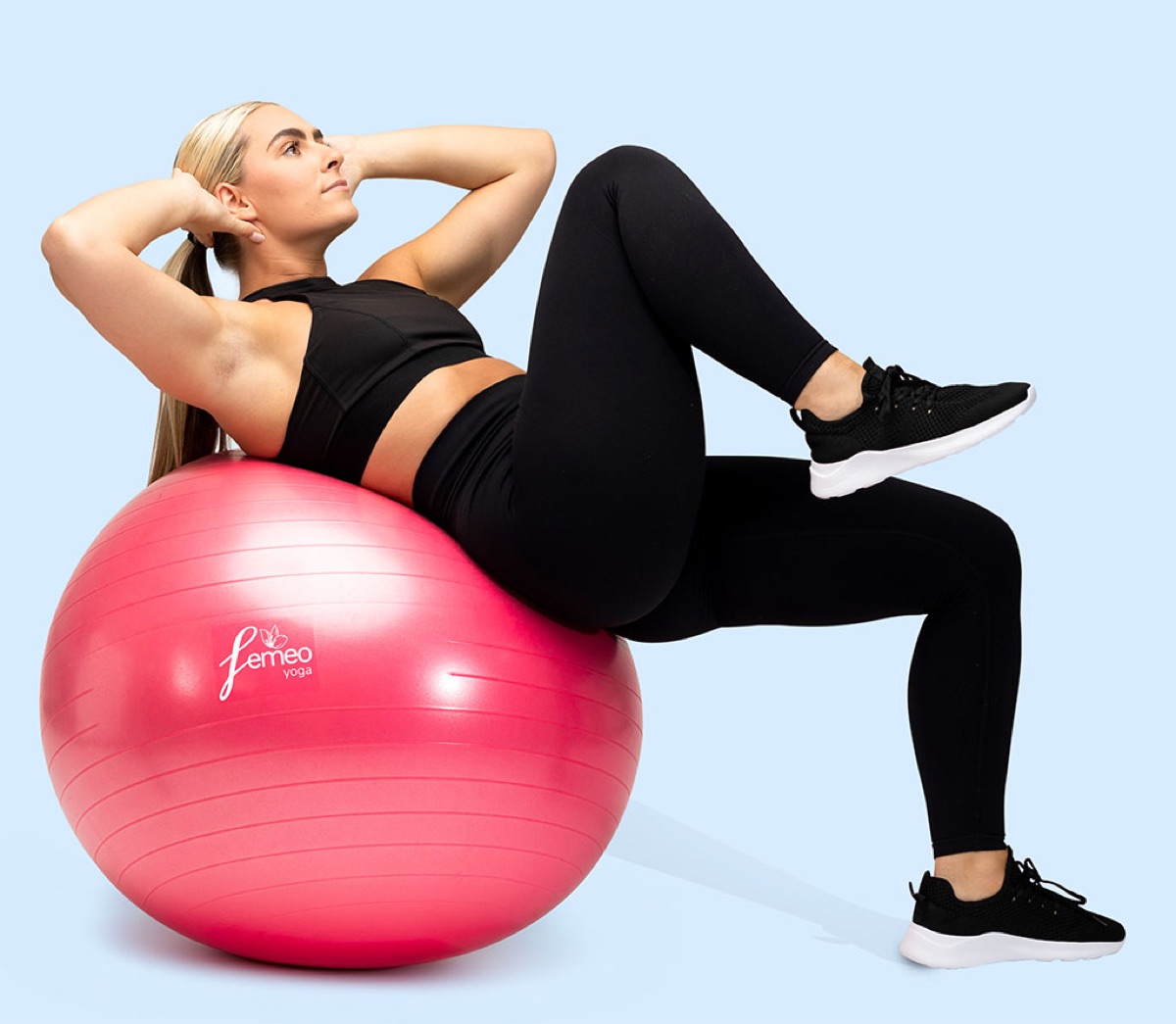 A woman training on a pink Femeo exercise ball